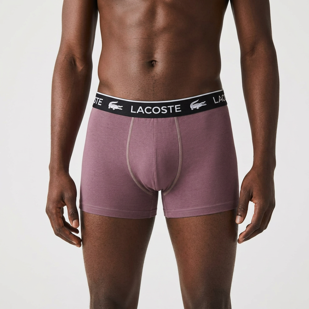 Male model wearing only muted plum boxer briefs on a plain studio background