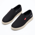 Pair of black slip-on sneakers with beige soles on white