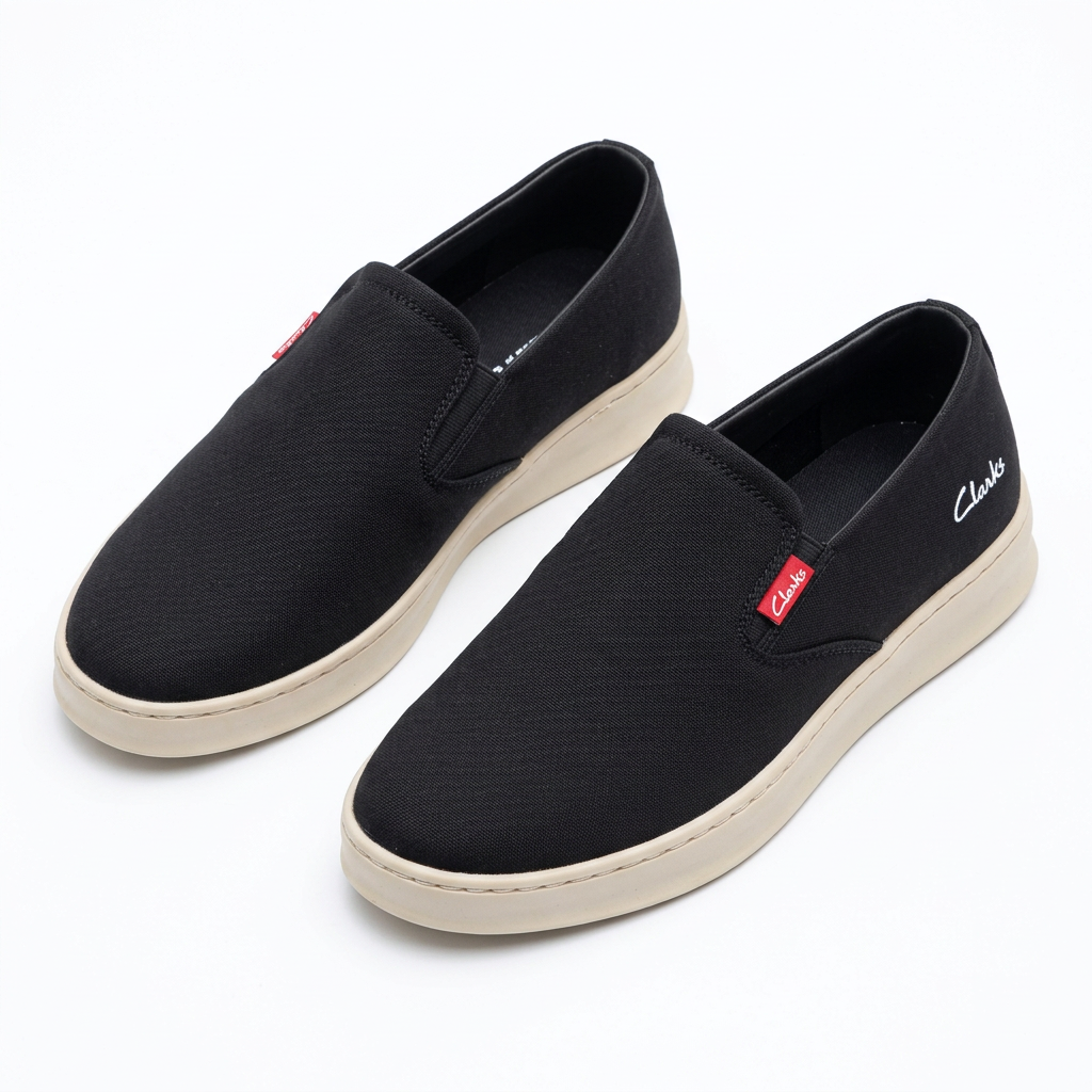 Pair of black slip-on sneakers with beige soles on white
