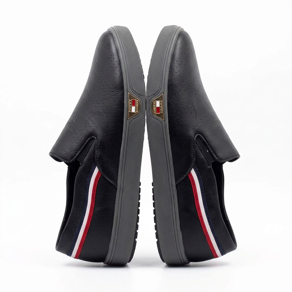 Pair of black perforated contrast-trim slip-on shoes on white background