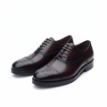 Pair of burgundy leather medallion cap toe oxford brogues on a white background