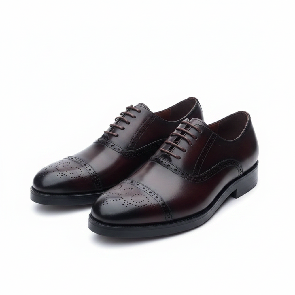 Pair of burgundy leather medallion cap toe oxford brogues on a white background