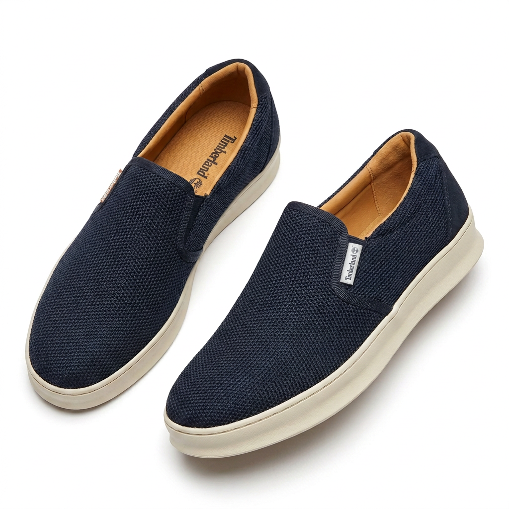 Pair of navy woven texture slip on sneakers with cream soles on white background