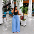 Nigerian female model wearing women's light blue high-waist wide-leg denim jeans, garden setting