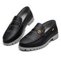 Pair of black contrast-stitch loafers with gold-tone emblems and grey lug soles on white
