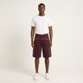 Male model wearing burgundy eyelet denim shorts with a white tee and trainers on a plain off-white background
