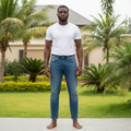 Adult Nigerian male model wearing faded blue wash straight leg denim jeans in garden setting