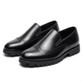 Pair of black brogue lug-sole slip-ons on a white background