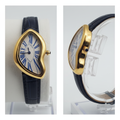 Asymmetric yellow gold watch with blue Roman numerals and navy strap front and side view