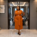 Nigerian woman wearing orange sleeveless belted midi dress in upscale setting