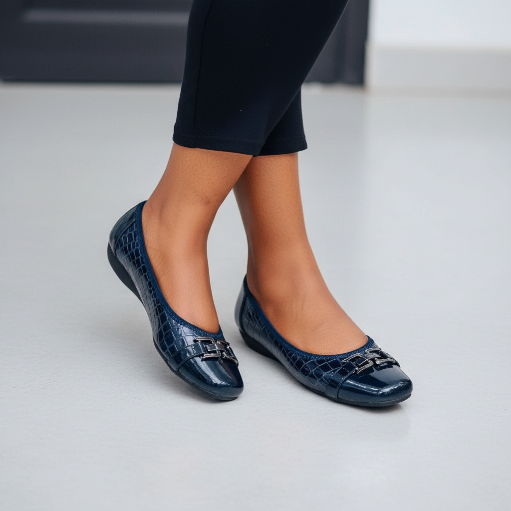 Close-up of Nigerian female legs in black midi skirt wearing navy croc-embossed patent ballet flats with chain-link bar detail
