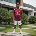 Nigerian child model wearing burgundy & white football jersey set with white football boots