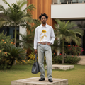 Nigerian male model wearing white fedora stick figure embroidered oversized long-sleeve shirt – full body lifestyle shot