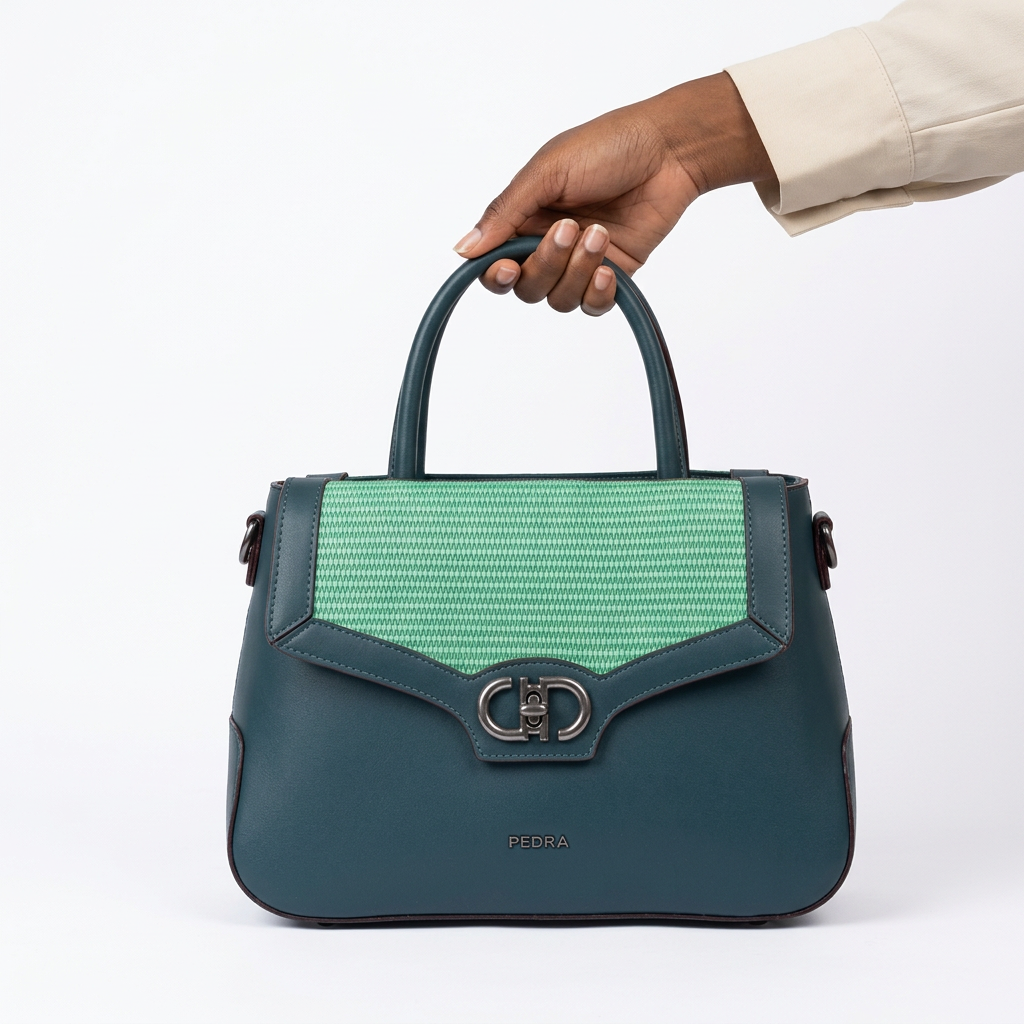 Black adult woman’s hand holding a teal and mint woven-panel handbag on white