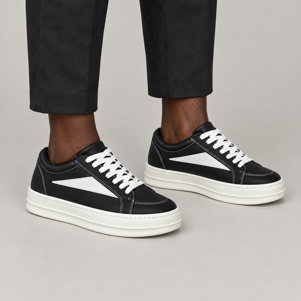 Both feet wearing black triangle-panel sneakers on plain background