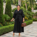 Nigerian female model wearing black ruffle sleeve belted pleated midi gown in garden setting