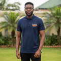 Nigerian male model wearing navy blue polo shirt with equestrian embroidery in garden setting