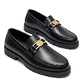 Pair of black gold-medallion loafers with zigzag apron stitching and black lug soles on white