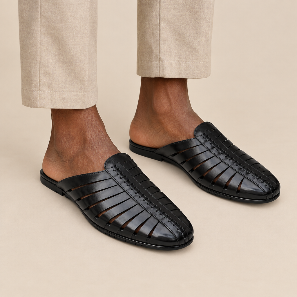 Black cutout slip-on mules worn with beige trousers, legs only