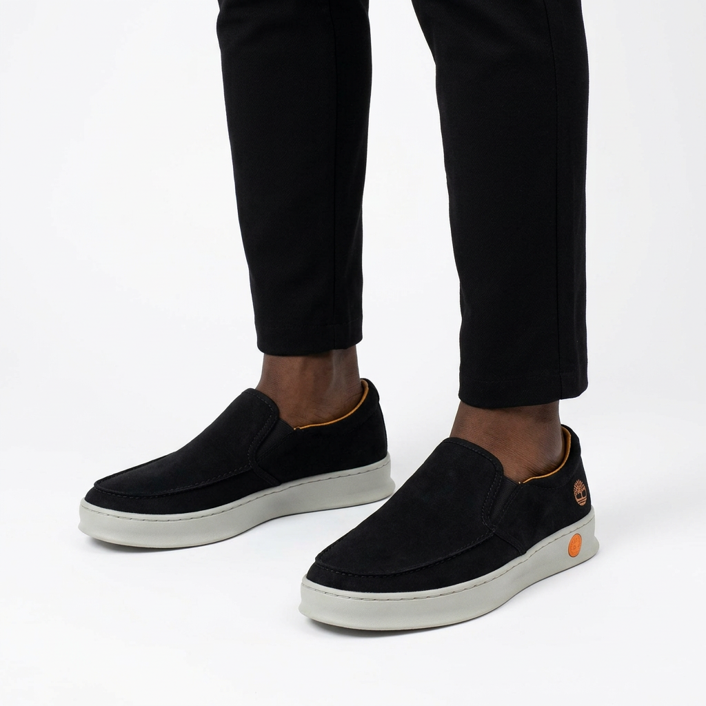 Black moc-toe slip-on shoes worn with black ankle trousers