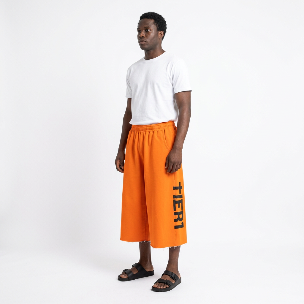 Full-body adult Black man wearing orange black-graphic wide-leg long shorts