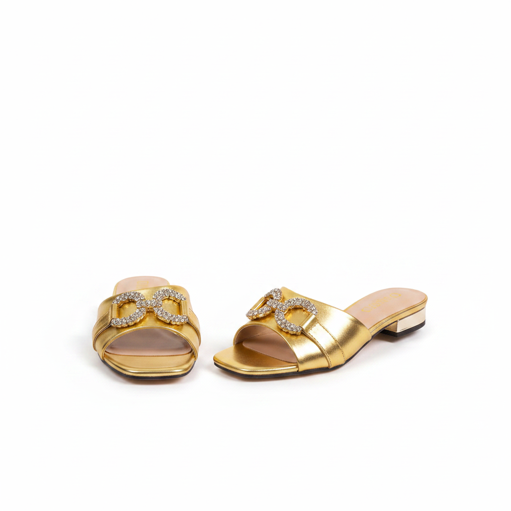 Pair of gold metallic square-toe low block heel mule sandals with crystal buckle on white background