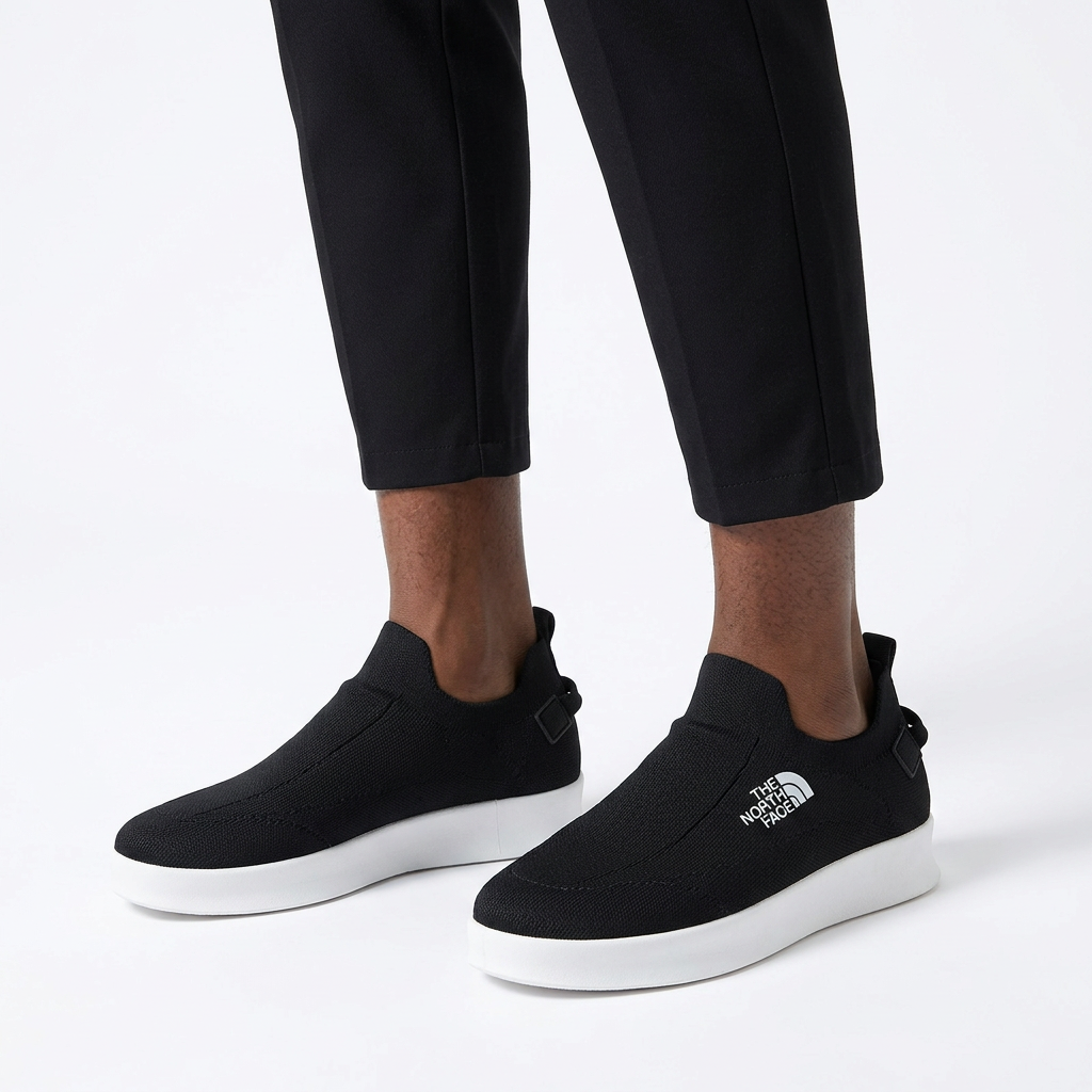 Black white-sole slip-on sneakers properly worn on both feet