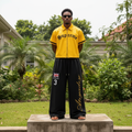 Nigerian male model wearing black gold script baggy wide-leg sweatpants – full body lifestyle shot