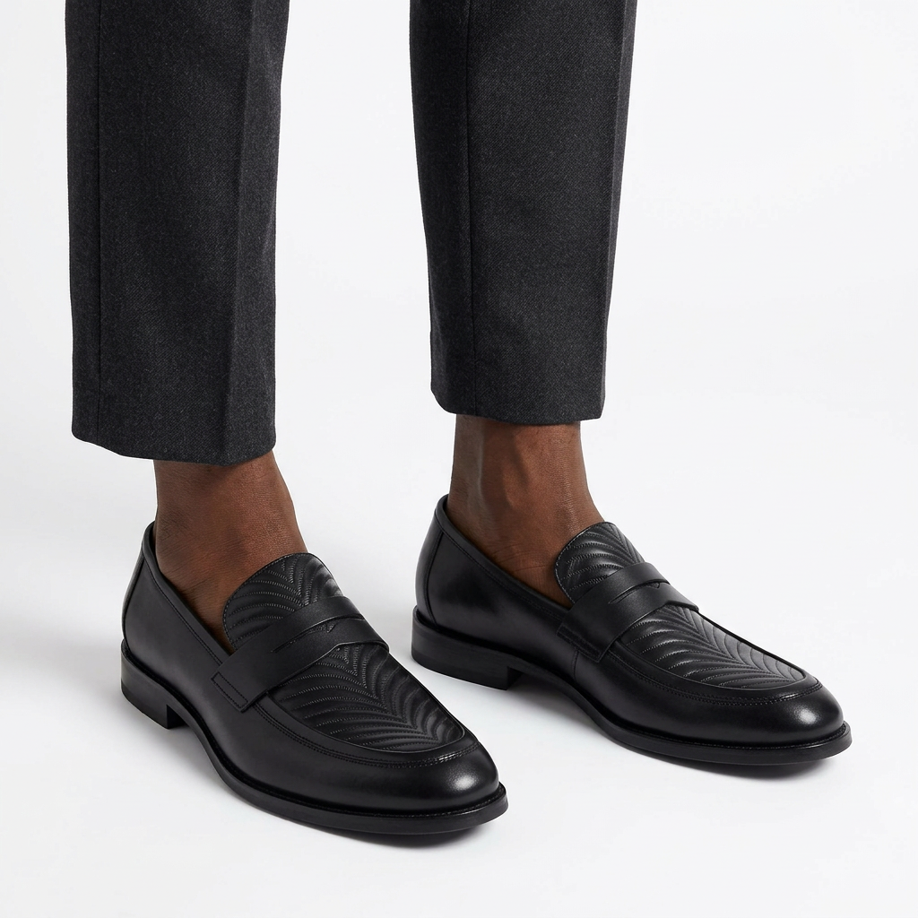 Both black embossed-vamp loafers worn with tailored trousers on white