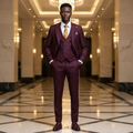 Young Nigerian male model wearing deep burgundy 3-piece suit with gold tie and pocket square