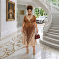 Nigerian female model wearing caramel brown and cream floral pleated midi gown in garden setting
