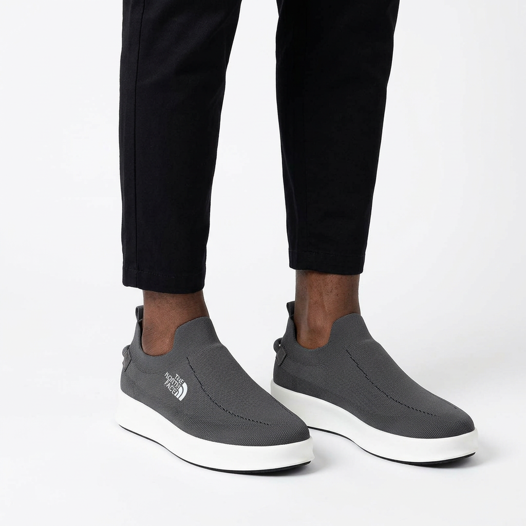 Charcoal white-sole slip-on sneakers properly worn on both feet