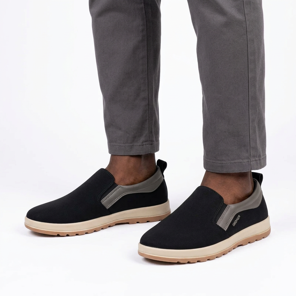 Black grey-trim slip-on shoes worn by a Nigerian male model on white