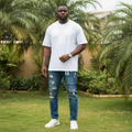 Nigerian male model wearing blue ripped denim jeans in outdoor setting