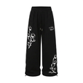 Black wide-leg drawstring trousers with contrasting white floral graphics