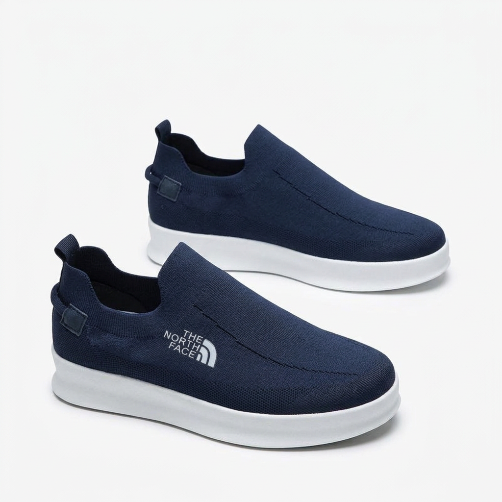 Pair of navy knit men’s slip-on shoes with white soles and heel pull tabs on white