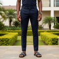 Nigerian male model wearing black woven Greek key stripe slide sandals with gold medallion in garden setting