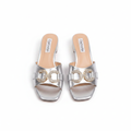 Pair of silver metallic square-toe low block heel mule sandals with gold crystal buckle on white background