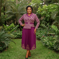 Nigerian female model wearing purple and gold jacquard blazer pleated midi gown in garden setting