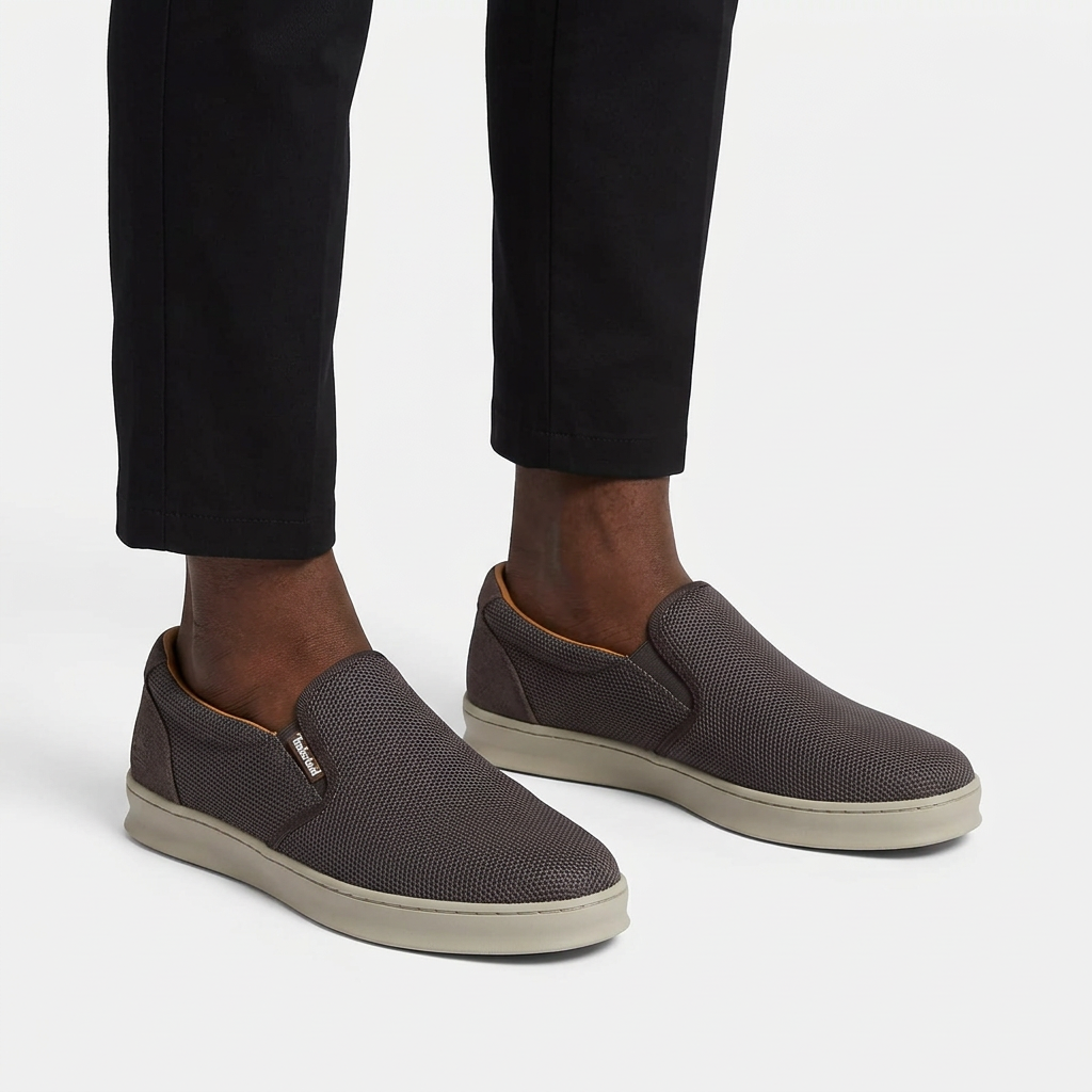 Charcoal-grey textured beige-sole slip-on sneakers properly worn on both feet