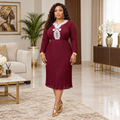 Woman wearing a burgundy pleated midi dress with white lace detail