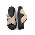 Pair of beige cross-strap platform slide sandals with silver studs and western buckle on white background