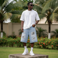 Nigerian male model wearing men's light blue heavily ripped distressed denim shorts streetwear style