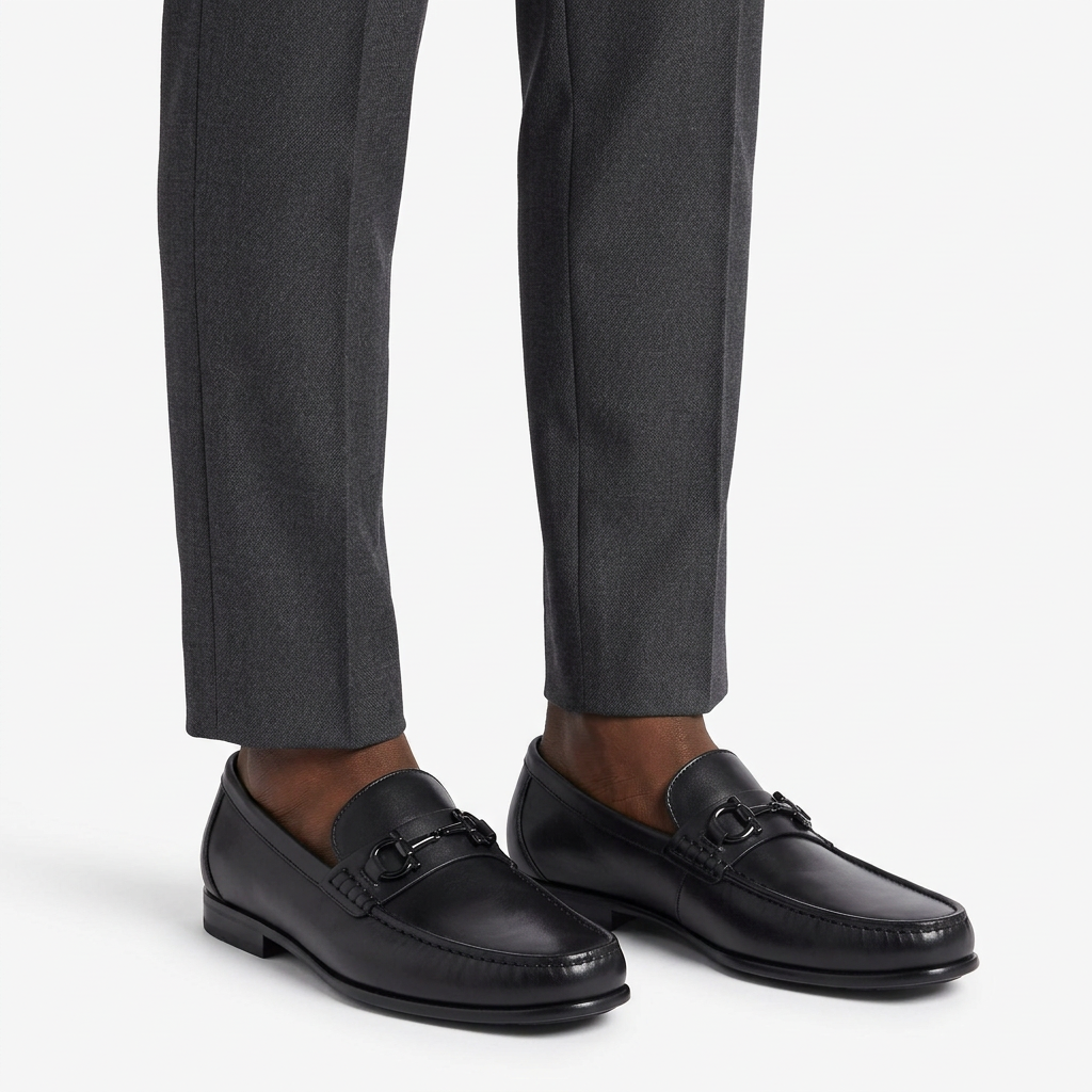 Smooth black metal-detail loafers worn on both feet with charcoal trousers