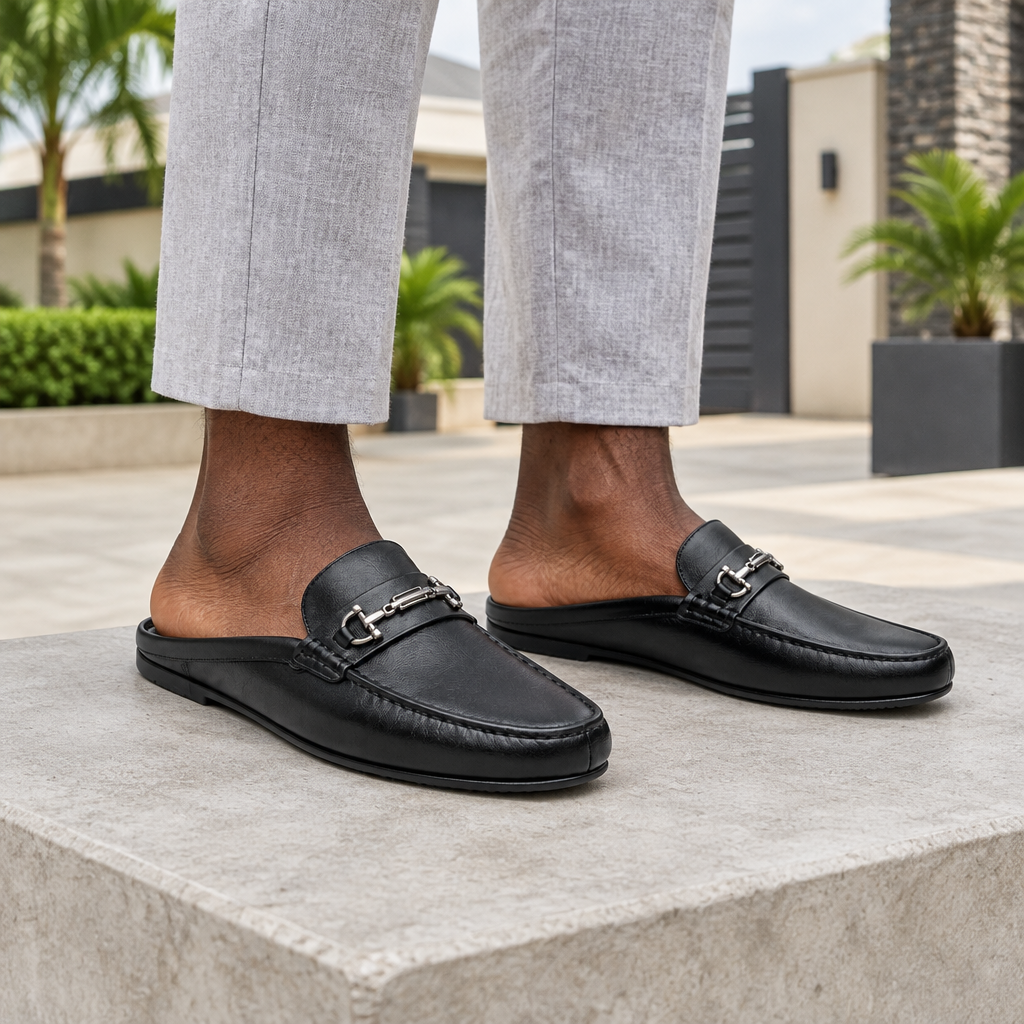 Man wearing black silver horsebit backless mule slippers with grey linen trousers