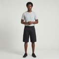 Full-body male model wearing black flap-pocket cargo shorts