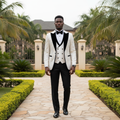 Nigerian male model wearing ivory white floral jacquard tuxedo three-piece suit with black velvet lapels