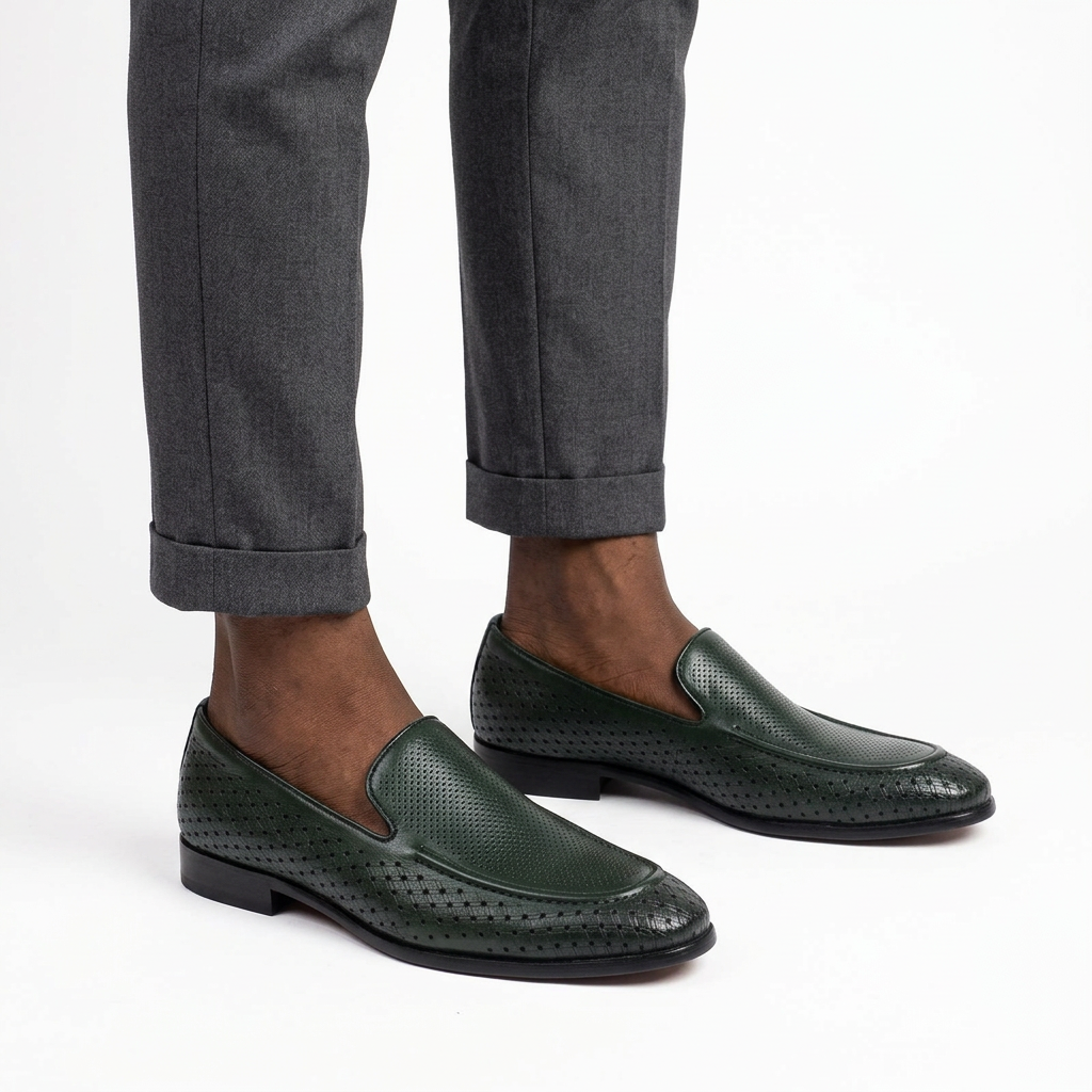 Dark green perforated slip-on loafers worn on both feet
