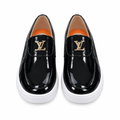 Front view of glossy black slip-on shoes with gold-tone details and white soles