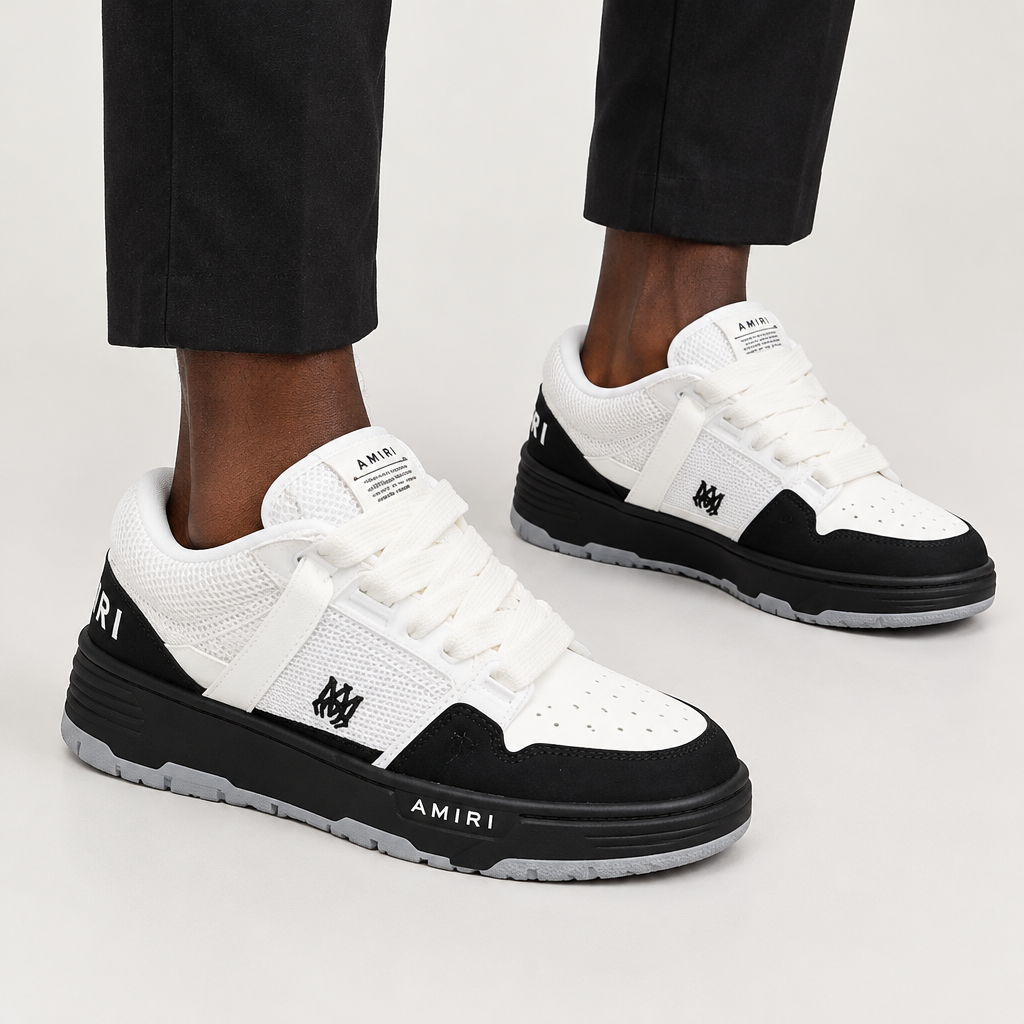 Both feet wearing black and white low-top sneakers on plain background
